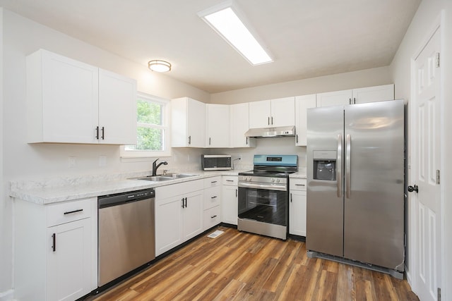1011 Bon Meade Dr, Burns, TN 37029 - kitchen with stainless steel appliances, under cabinet range hood, a sink, white cabinets, and dark wood finished floors