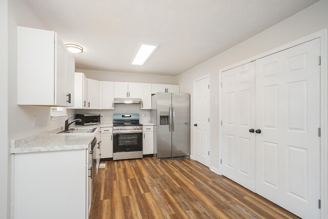 1011 Bon Meade Dr, Burns, TN 37029 - kitchen featuring stainless steel appliances, under cabinet range hood, a sink, light countertops, and dark wood finished floors
