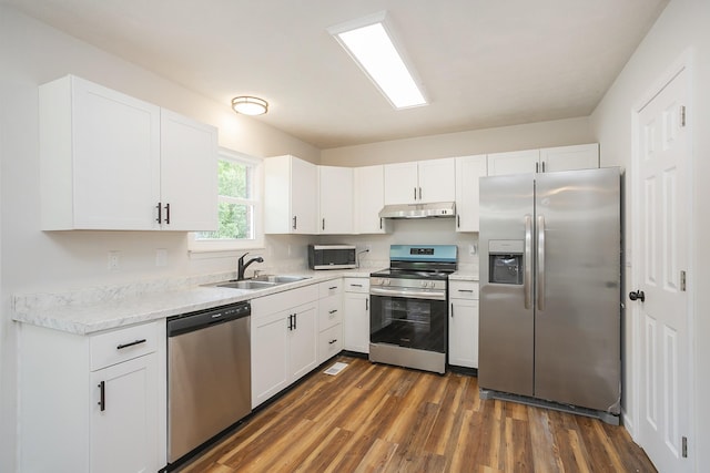 1011 Bon Meade Dr, Burns, TN 37029 - kitchen featuring appliances with stainless steel finishes, under cabinet range hood, a sink, dark wood finished floors, and white cabinets