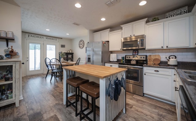 3307 Stormello Ln, Murfreesboro, TN 37128 - kitchen with stainless steel appliances, butcher block countertops, a breakfast bar, white cabinets, and wood finished floors