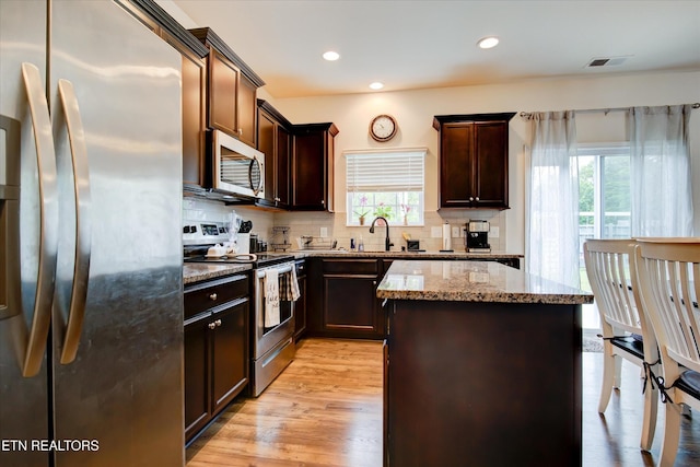 1242 Bill Wallace Dr, Friendsville, TN 37737 - kitchen featuring stainless steel appliances, light stone countertops, a kitchen island, a sink, and backsplash