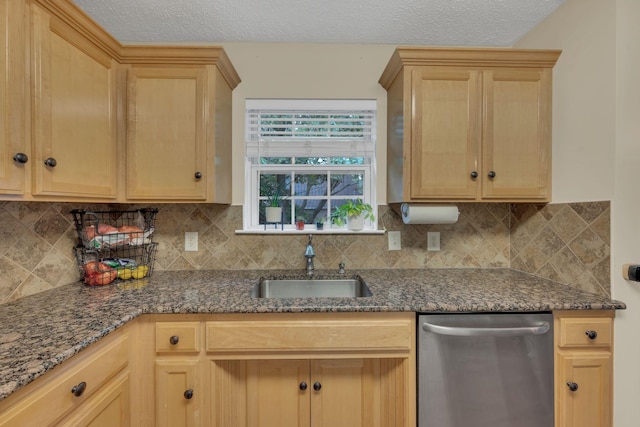 kitchen featuring stainless steel dishwasher, a sink, light brown cabinets, and a textured ceiling