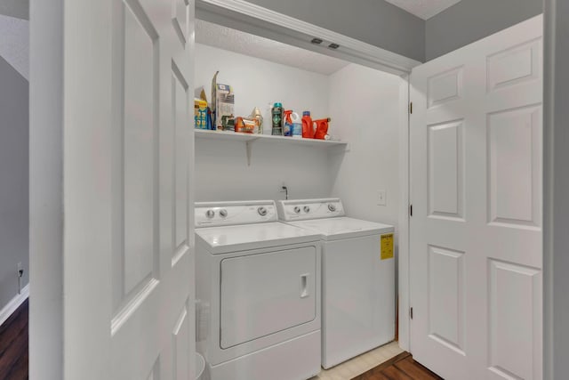 clothes washing area featuring washer and dryer, wood finished floors, and a textured ceiling
