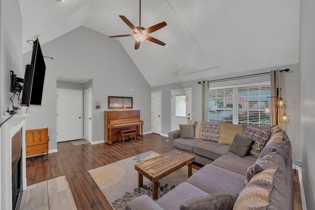 living room with a ceiling fan, high vaulted ceiling, wood finished floors, and baseboards