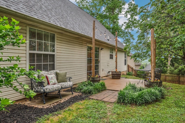 rear view of property with roof with shingles, a patio, and fence