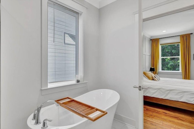 ensuite bathroom featuring a freestanding bath and baseboards