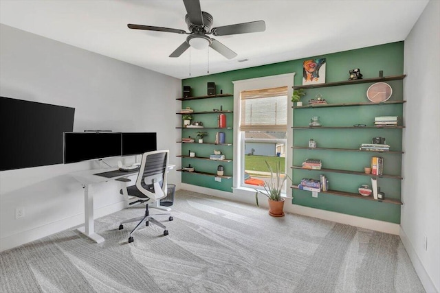 carpeted office space with ceiling fan and baseboards