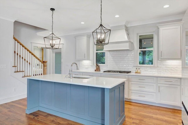 kitchen featuring a sink, stainless steel gas cooktop, a chandelier, backsplash, and crown molding