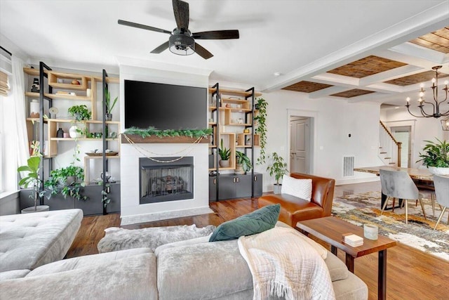 living area featuring stairs, a ceiling fan, coffered ceiling, beam ceiling, and a fireplace