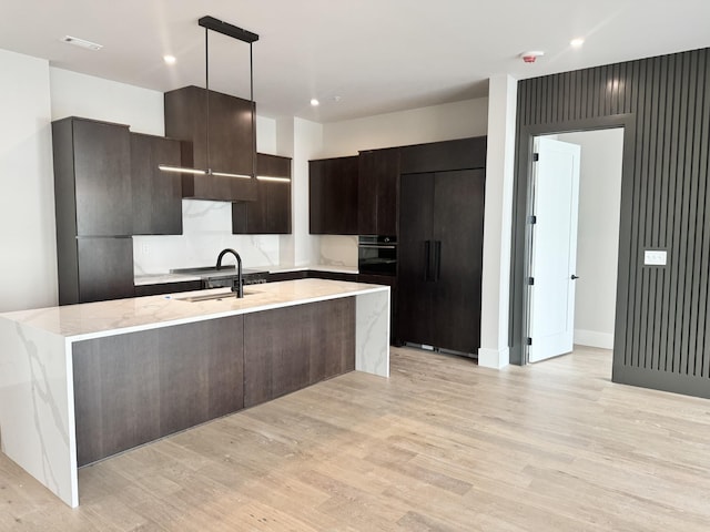 kitchen with paneled built in fridge, modern cabinets, black oven, light wood-type flooring, and recessed lighting
