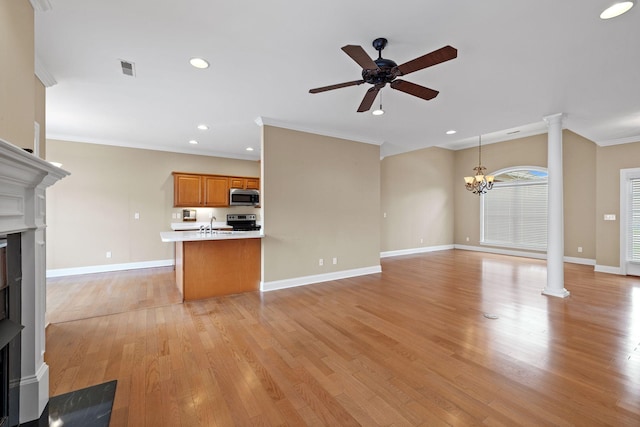 153 Magnolia Glen Cir, Manchester, TN 37355 - unfurnished living room featuring decorative columns, a ceiling fan, ornamental molding, light wood-type flooring, and a chandelier