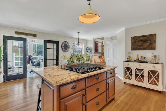 213 Hickory Trl, White House, TN 37188 - kitchen with black gas stovetop, light wood-style floors, healthy amount of natural light, brown cabinets, and ornamental molding