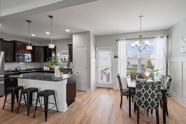 5902 Covent Ln, Smyrna, TN 37167 - kitchen featuring appliances with stainless steel finishes, a chandelier, a breakfast bar area, dark brown cabinets, and light wood-type flooring