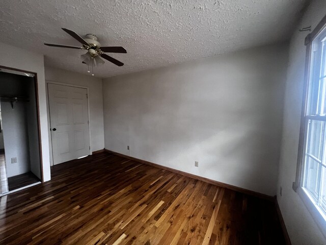 555 Oakley Allons Rd, Allons, TN 38541 - unfurnished bedroom featuring dark wood-style floors, a textured ceiling, baseboards, a closet, and multiple windows