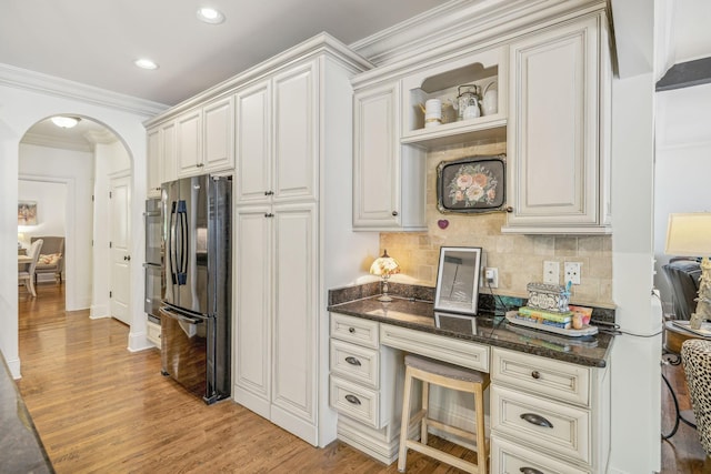 5432 Parker Branch Rd, Franklin, TN 37064 - kitchen with freestanding refrigerator, arched walkways, decorative backsplash, light wood-style flooring, and dark stone countertops