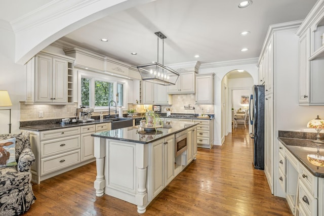 5432 Parker Branch Rd, Franklin, TN 37064 - kitchen featuring arched walkways, a kitchen island, a sink, backsplash, and ornamental molding