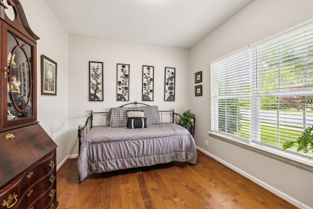 bedroom with dark wood-style flooring, multiple windows, and baseboards