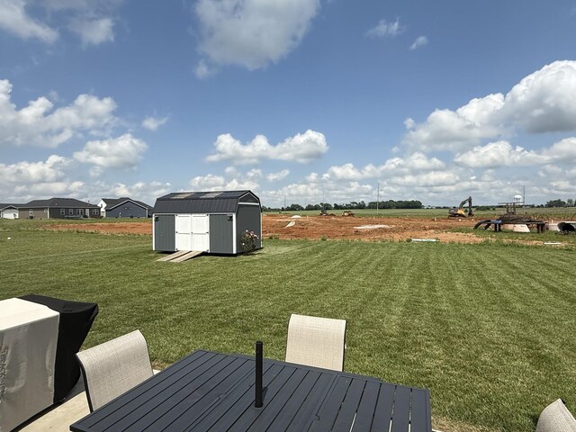 view of grassy yard featuring a shed, an outdoor structure, and outdoor dining space