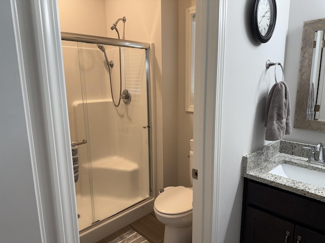bathroom with a shower stall, toilet, and vanity