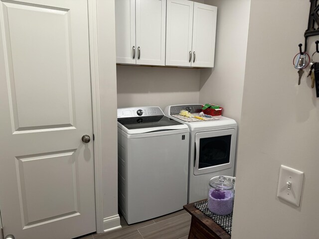 laundry room with washing machine and dryer, cabinet space, and wood tiled floors