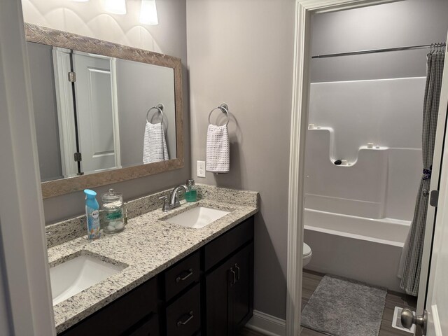 bathroom with double vanity, toilet, and shower / bath combo
