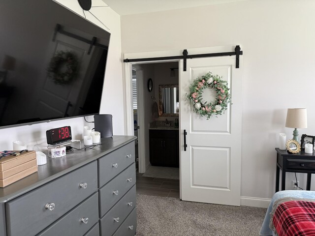 bedroom with a barn door, carpet, baseboards, and a sink