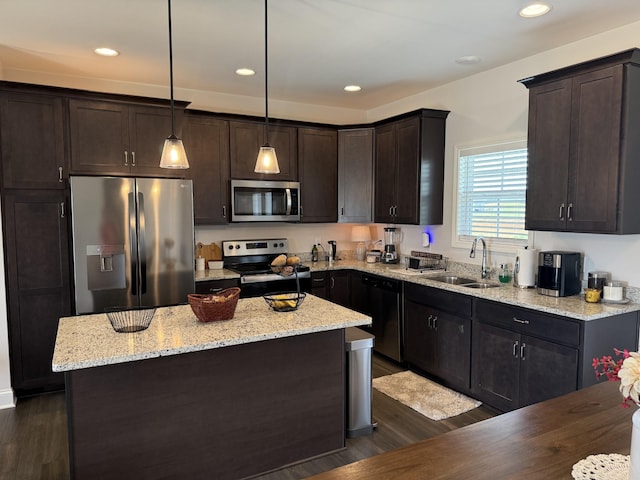kitchen featuring appliances with stainless steel finishes, a sink, dark brown cabinets, dark wood-style flooring, and a center island