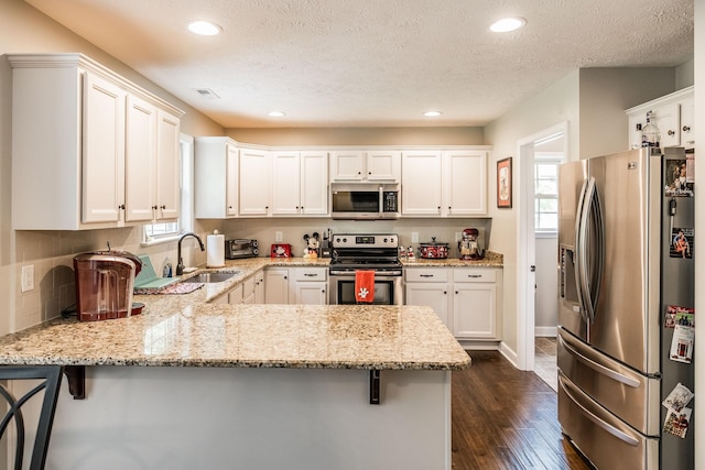 1461 Round Rock Dr, Murfreesboro, TN 37128 - kitchen featuring stainless steel appliances, a sink, a peninsula, dark wood-type flooring, and white cabinetry