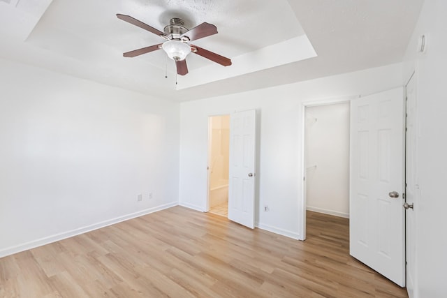 7004 Westfork Dr, Smyrna, TN 37167 - unfurnished bedroom featuring a walk in closet, light wood-style floors, a raised ceiling, and baseboards