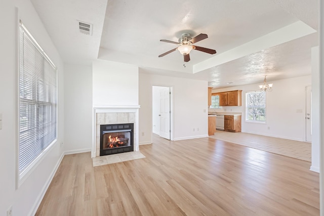 7004 Westfork Dr, Smyrna, TN 37167 - unfurnished living room with light wood-style flooring, a tile fireplace, ceiling fan, a tray ceiling, and a chandelier