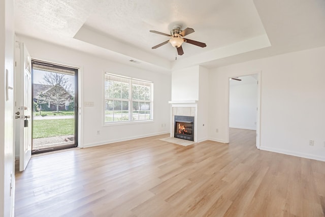 7004 Westfork Dr, Smyrna, TN 37167 - unfurnished living room with a raised ceiling, a fireplace, light wood finished floors, a ceiling fan, and baseboards