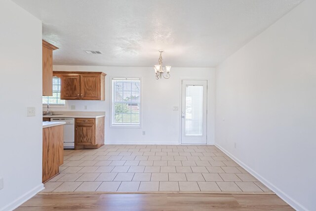 7004 Westfork Dr, Smyrna, TN 37167 - kitchen featuring white dishwasher, a chandelier, light countertops, baseboards, and brown cabinets