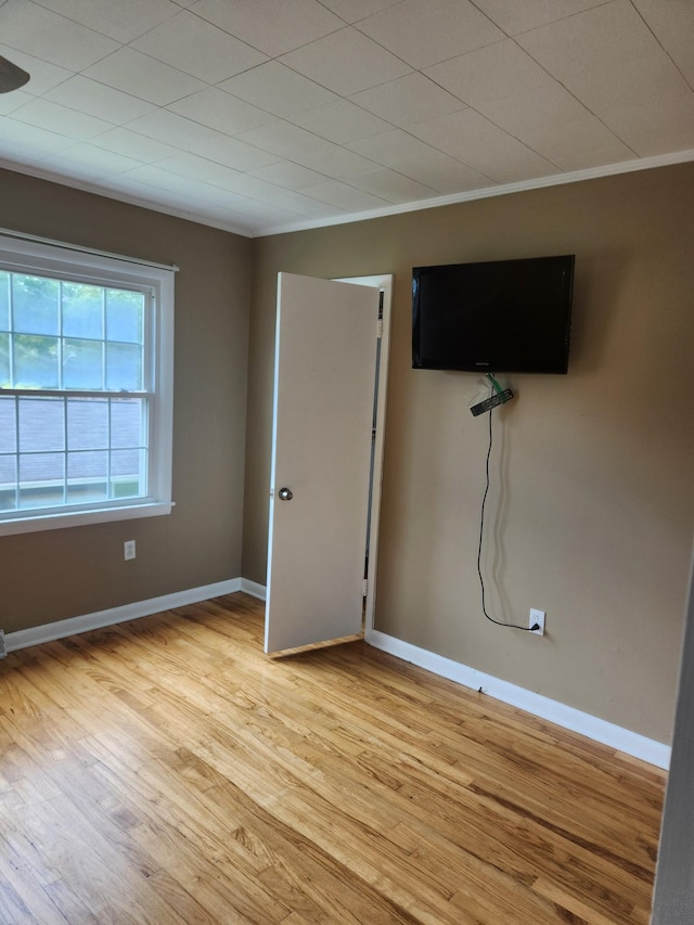 unfurnished bedroom featuring light wood-type flooring, ornamental molding, and baseboards