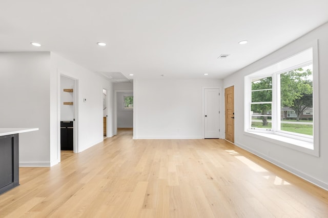 unfurnished living room with healthy amount of natural light, light wood finished floors, and recessed lighting
