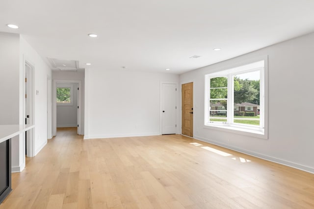 empty room featuring attic access, light wood finished floors, baseboards, and recessed lighting
