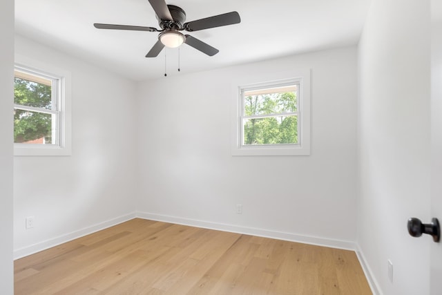 spare room with healthy amount of natural light, baseboards, light wood-type flooring, and a ceiling fan