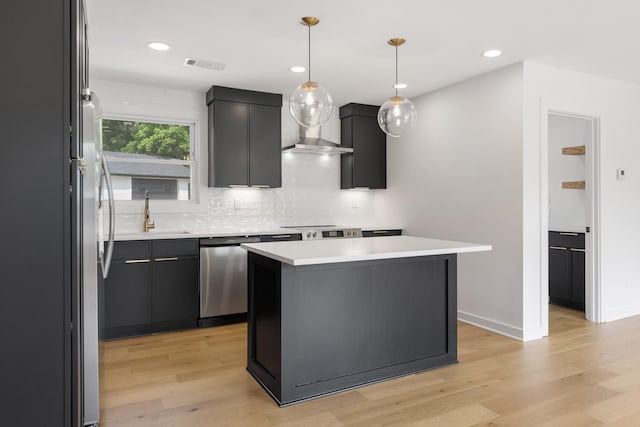 kitchen featuring appliances with stainless steel finishes, a sink, light wood-type flooring, backsplash, and recessed lighting