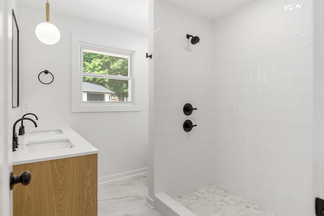 full bathroom featuring marble look tiles, tiled shower, double vanity, and baseboards
