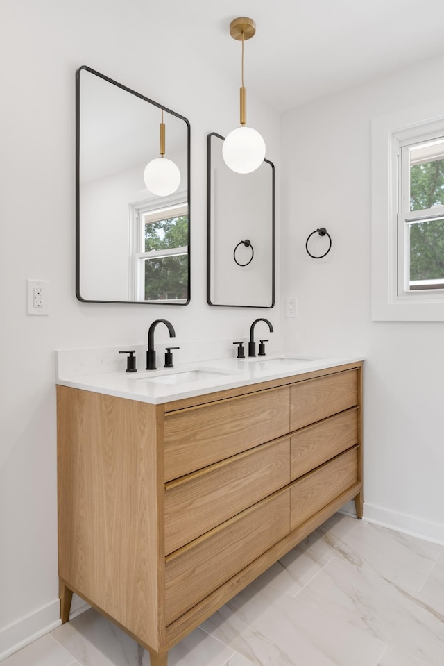 bathroom with double vanity, baseboards, and marble finish floors
