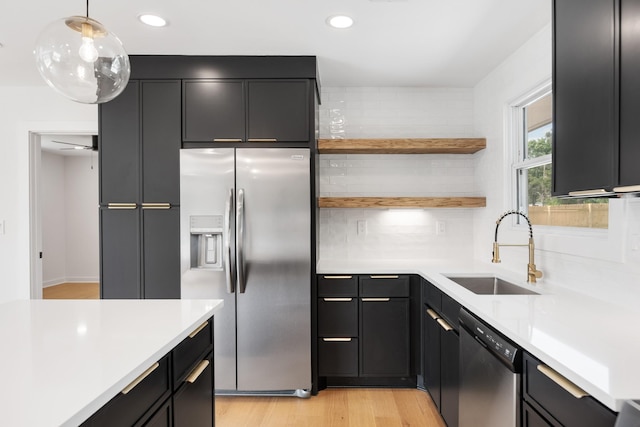 kitchen featuring stainless steel appliances, a sink, light countertops, dark cabinetry, and recessed lighting