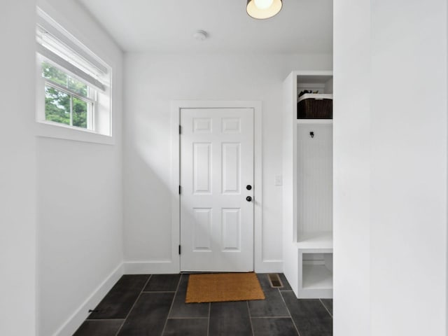 entrance foyer with dark tile patterned flooring and baseboards