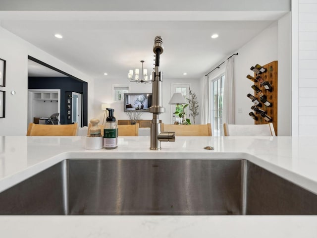 kitchen view of a chandelier, recessed lighting, light stone countertops, and hanging light fixtures