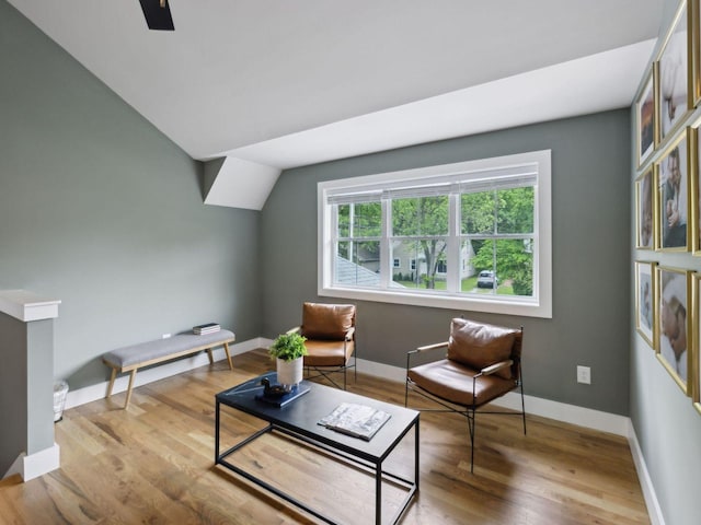 sitting room featuring wood finished floors, vaulted ceiling, and baseboards