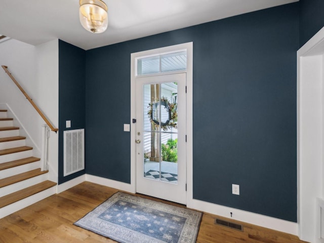foyer featuring stairs, wood finished floors, and baseboards