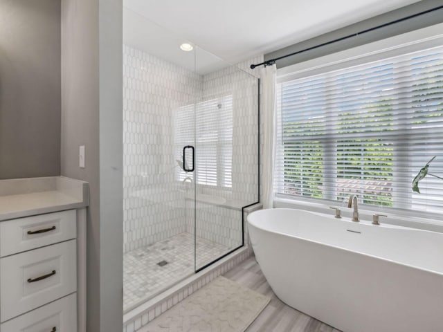 bathroom with a shower stall, a soaking tub, and wood finished floors