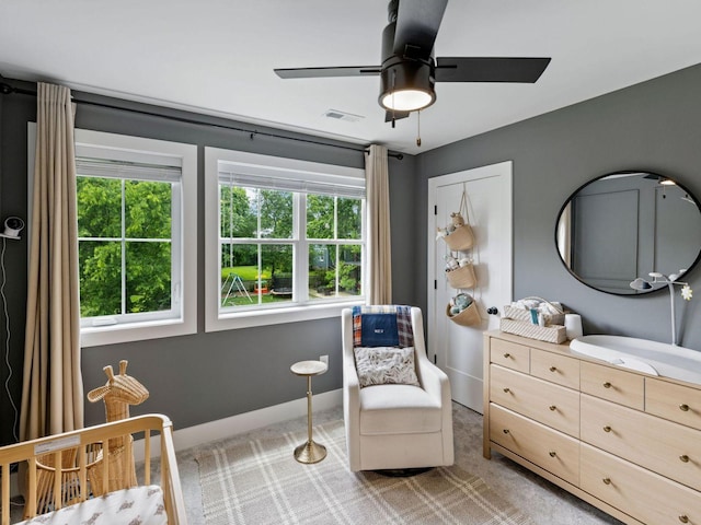 bedroom featuring light colored carpet, multiple windows, baseboards, and a ceiling fan