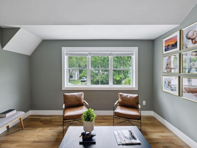 living area featuring lofted ceiling, wood finished floors, and baseboards