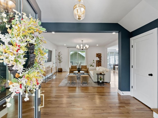 living area featuring a chandelier, wood finished floors, vaulted ceiling, and baseboards