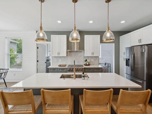 kitchen featuring stainless steel appliances, wall chimney exhaust hood, light countertops, pendant lighting, and recessed lighting