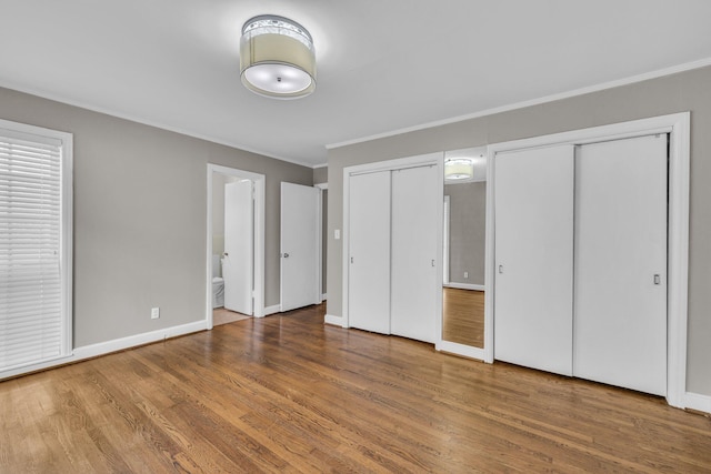 519 S Scott St, Scottsboro, AL 35768 - unfurnished bedroom featuring two closets, ornamental molding, wood finished floors, ensuite bathroom, and baseboards